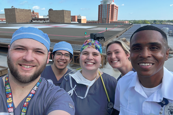 Residents in scrubs on a rooftop with buildings in the background