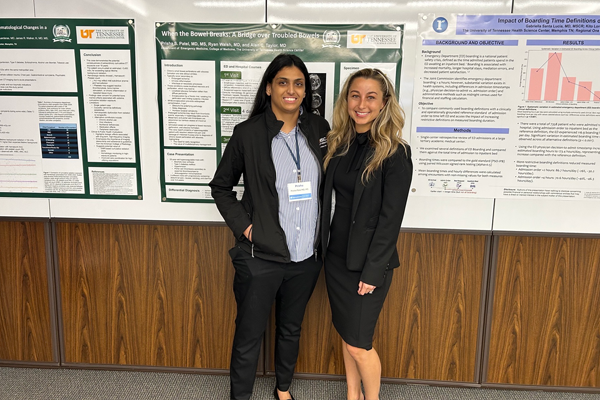 Two female residents standing before a poster presentation