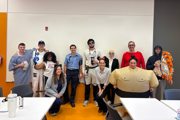 Group of male and female residents dressed in costumes in front of a classroom