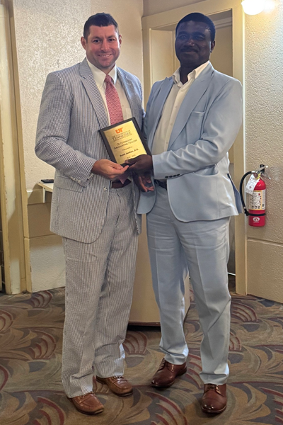Graduate holding a plaque and faculty posing together