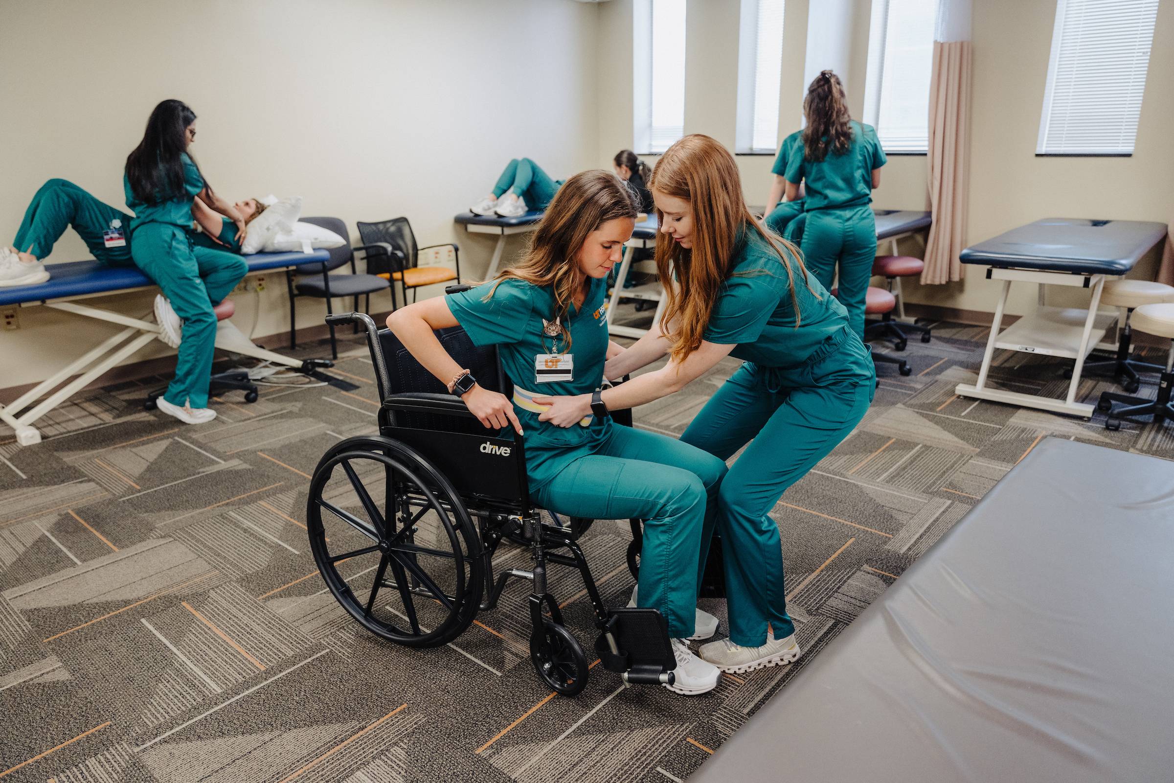 OT students practicing as both therapist and patients in wheelchair and getting out of beds.