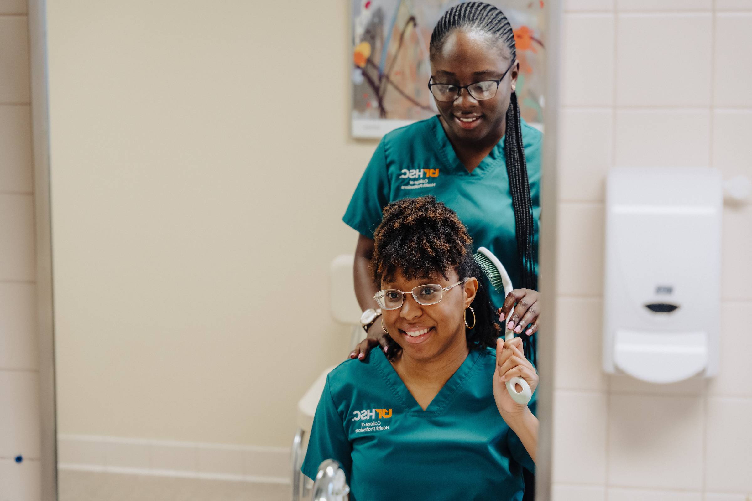 OT students praciticing being a patient as they look in a mirror to comb their hair.