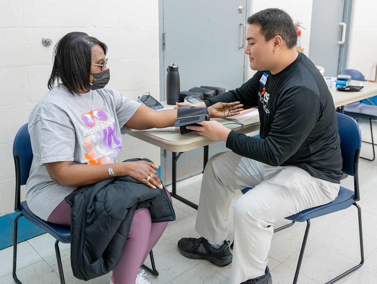 Commuity member getting a health screening involving getting their blood pressure taken.