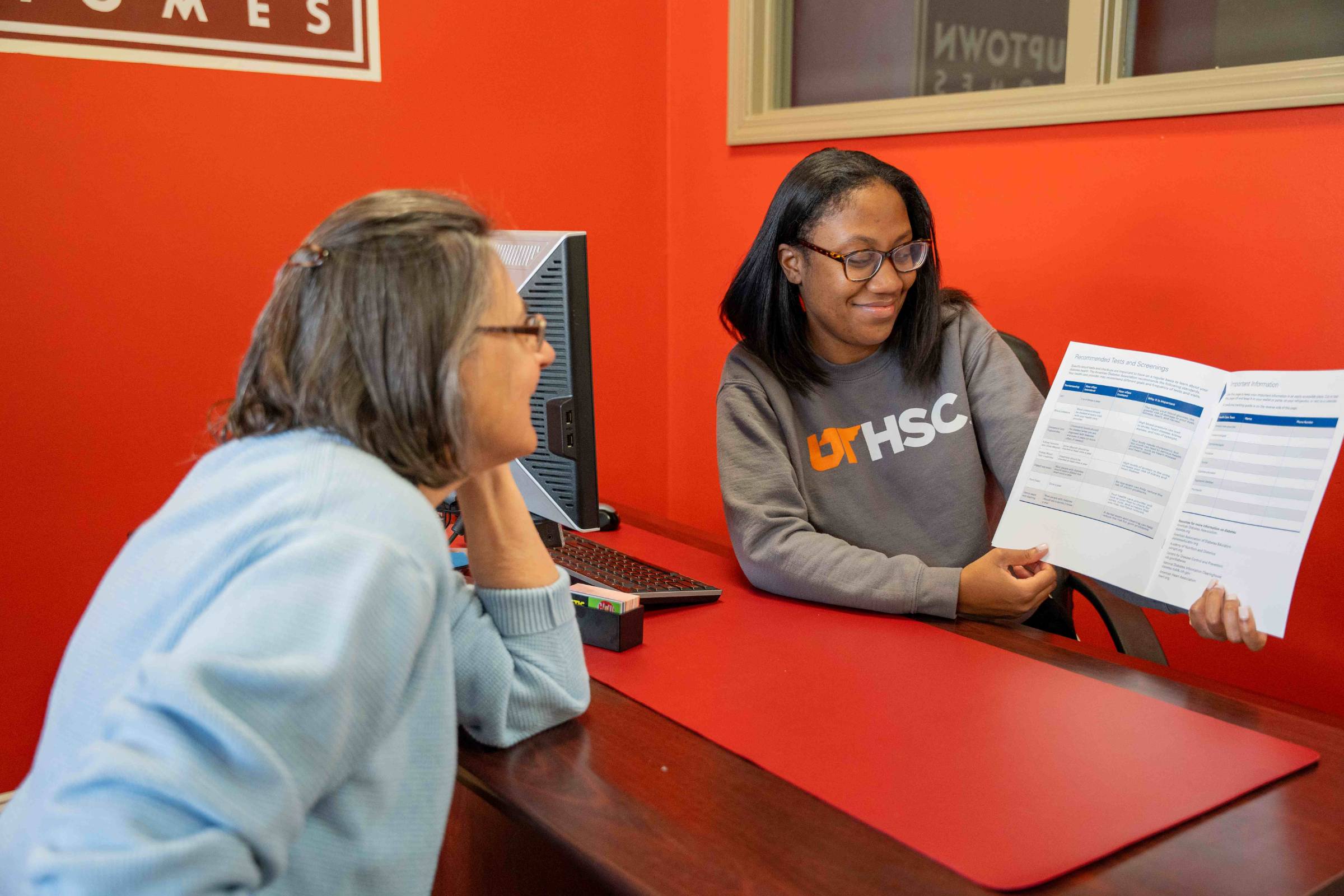 Staff explaining information in a booklet to a member of the public.