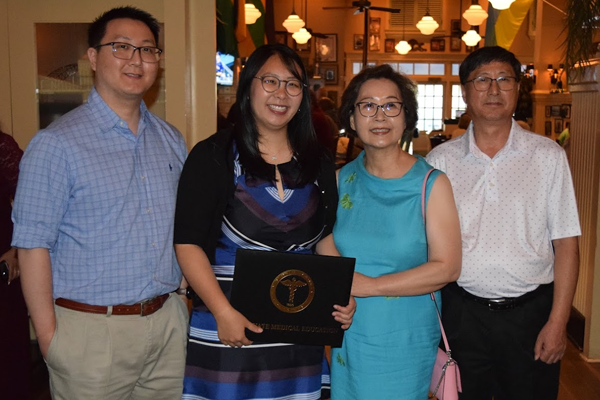 Female fellow holding certicate surrounded by family