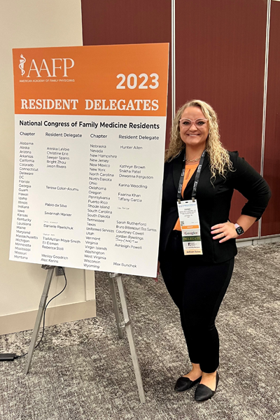 Female resident standing before a presentation poster