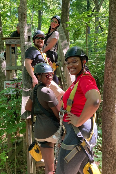 Residents getting ready to go ziplining in a woodsy setting