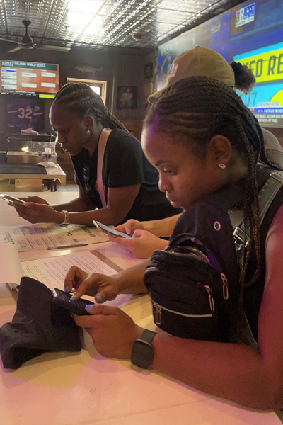 three residents sitting at a table, looking at their phones