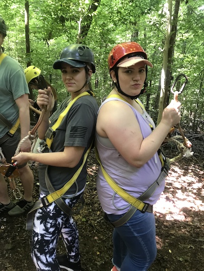 2 female resident outdoors in ziplining equipment