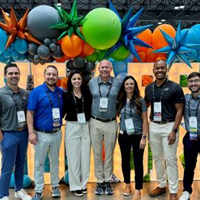 Residents and faculty inside the conference with colorful balloons in the background