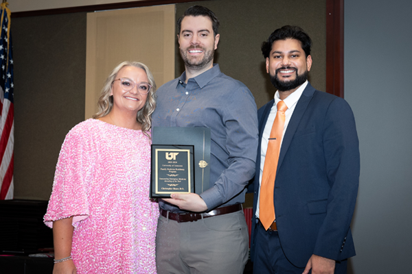 Two male and a female resident holding an award