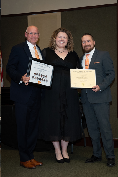 Faculty standing with a resident holding a certificate