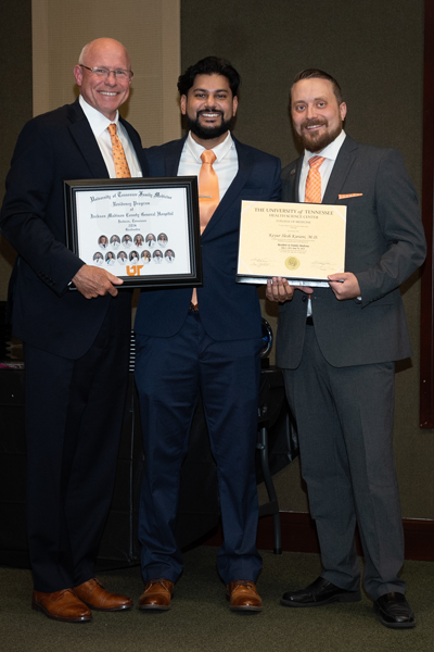 Faculty standing with a resident holding a certificate