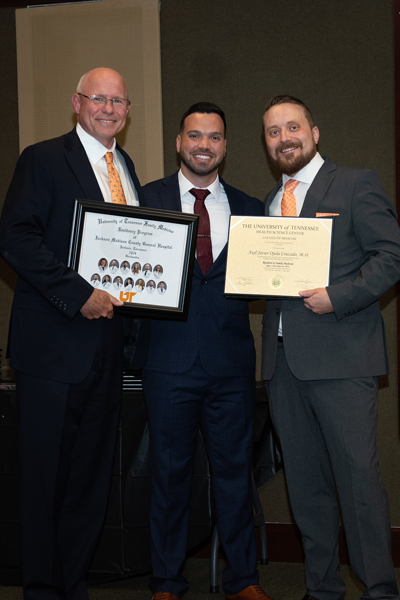 Faculty standing with a resident holding a certificate