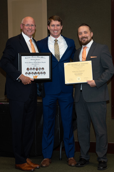 Faculty standing with a resident holding a certificate