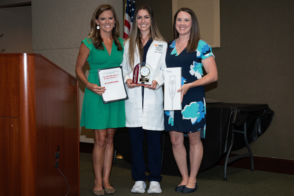 Three female residents holding certificates and awards