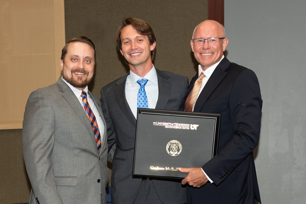 Resident holding a certificate with faculty at graduation