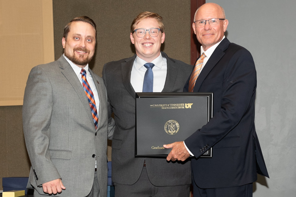 Resident holding a certificate with faculty at graduation