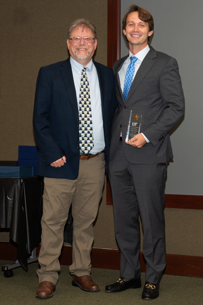 Faculty and resident hold an award at graduation