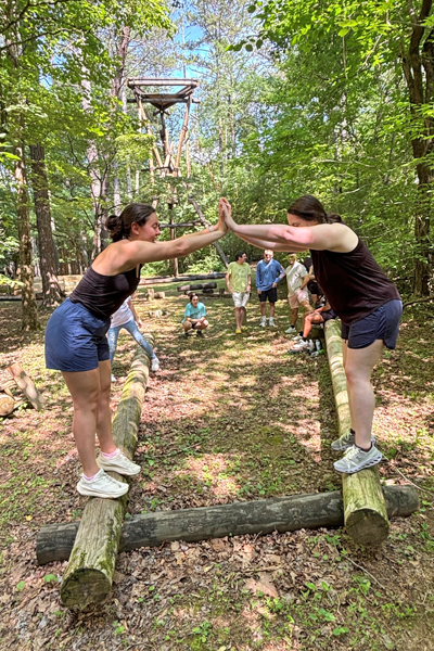 Residents on logs holding hands in an outdoor training exercise