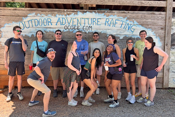 Outside group photo of residents in front of a wooden sign