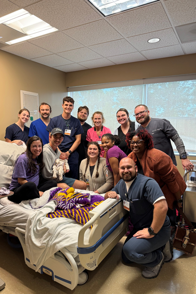 Female residents and faculty holding a baby dummy in a hospital setting