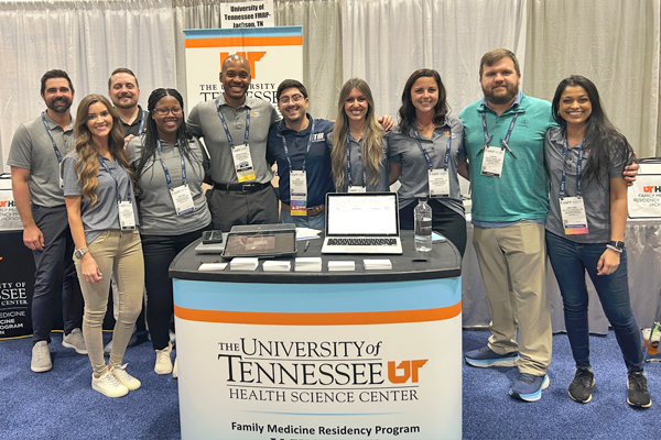 Residents and faculty standing around the UTHSC booth