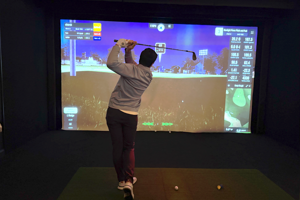 A male resident playing a similated golf game