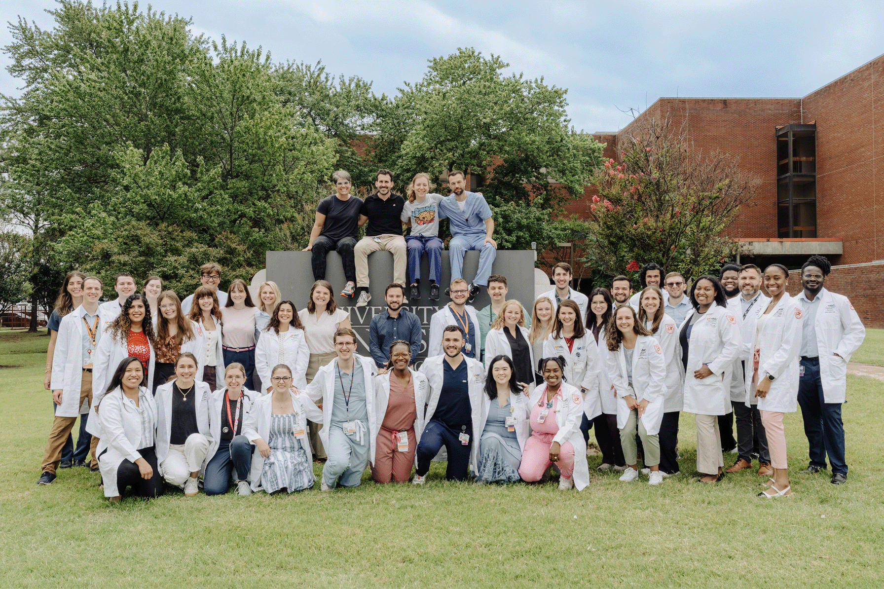 Med Peds residents and faculty posing outside between buildings on a sunny day