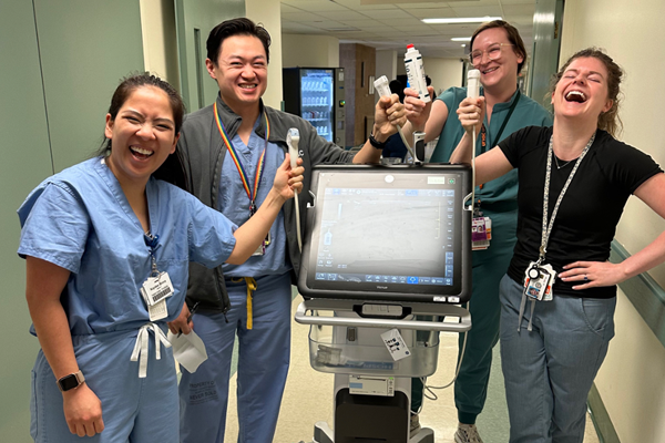 Residents in scrubs with some equipment in a hospital hallway