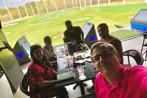 Fellows eating outdoors at Top Golf