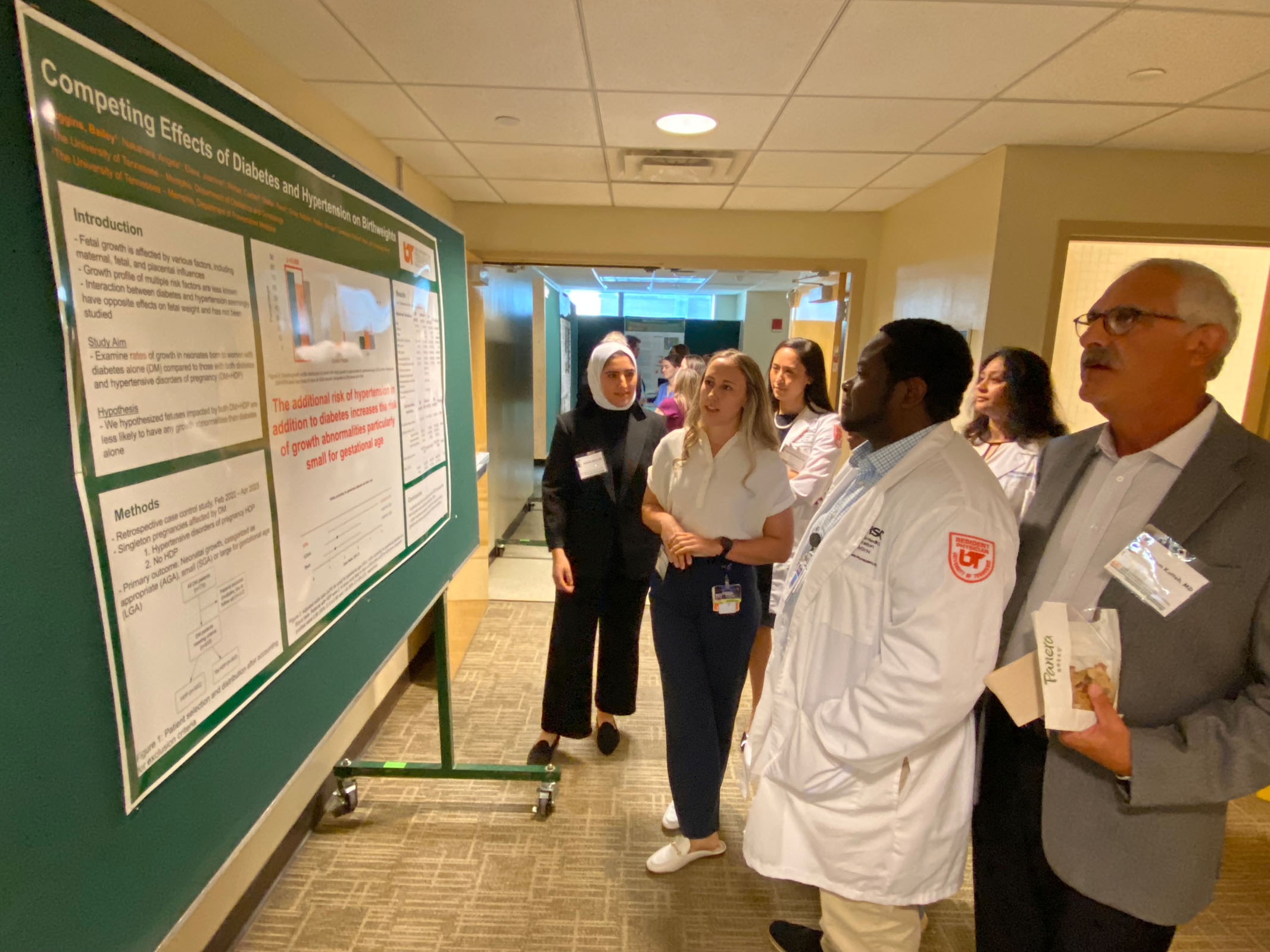 Faculty and students reviewing a presentation board at the 2024 Research Forum.