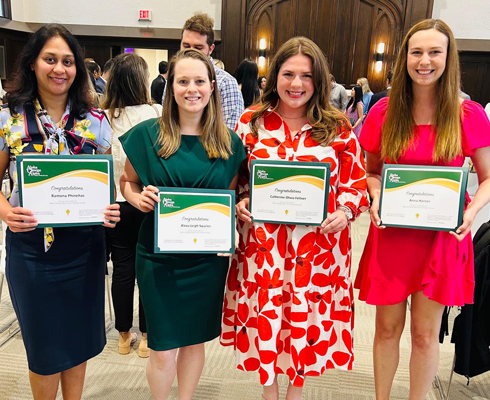 Four female residents holding certificates