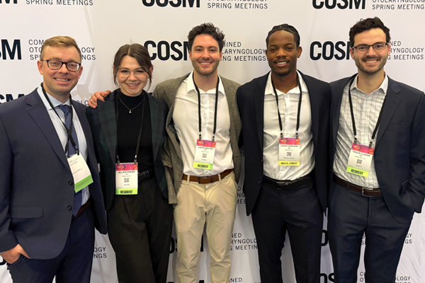 Residents posing against a wall at a conference