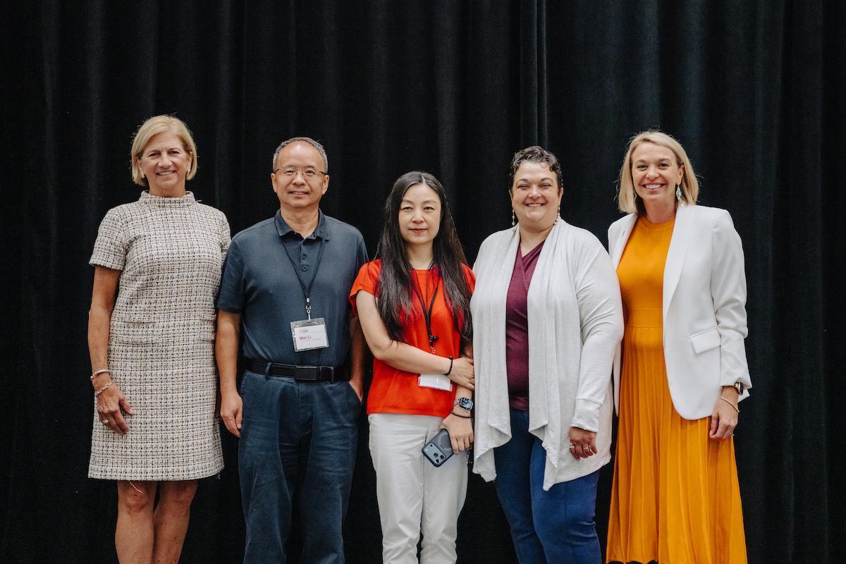 4 Cancer Discovery Fund Award winners standing before a black curtain