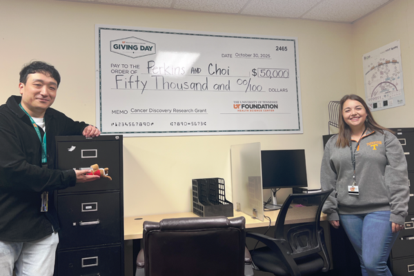 Drs. Choi and Perkins standing in an office setting with a large $50,000 check for their research