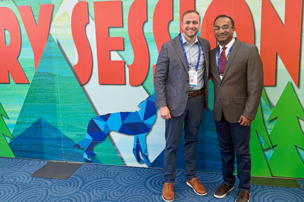 Fellow and faculty members standing before a conference banner