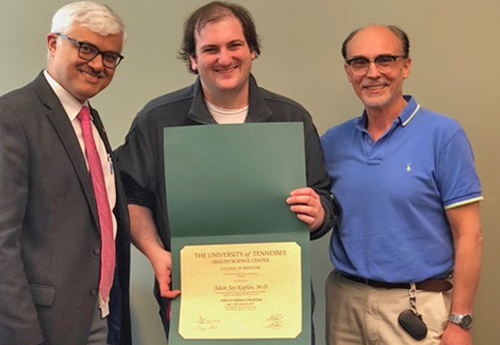 Fellow standing by two faculty members while holding a certificate 