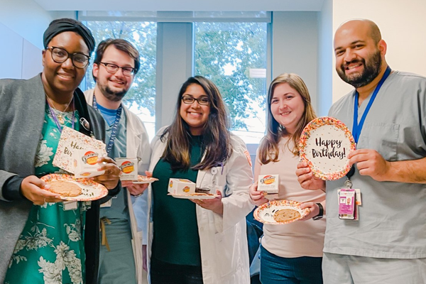 Five residents holding happy birthday cookies