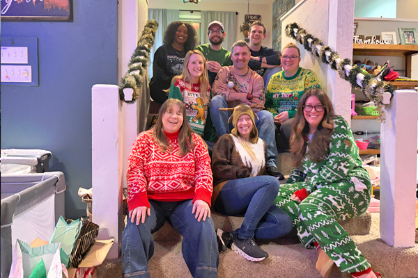 Group of fellows wearing festive holiday pajamas and posing on a staircase