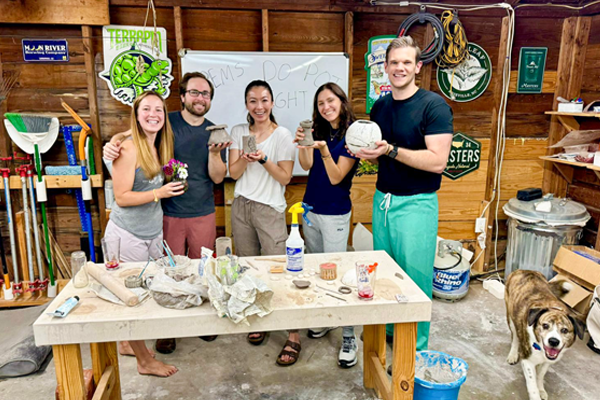 Five fellows displaying ceramic creations during a pottery workshop in a studio