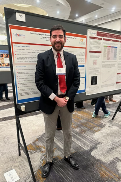 Resident standing before a poster presentation