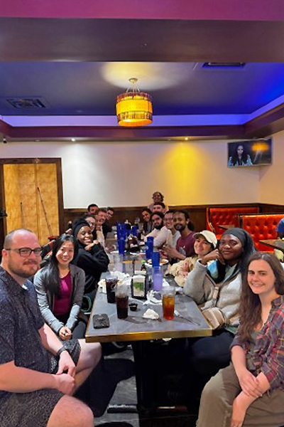 Residents sit together around a long table during a group dinner at a restaurant