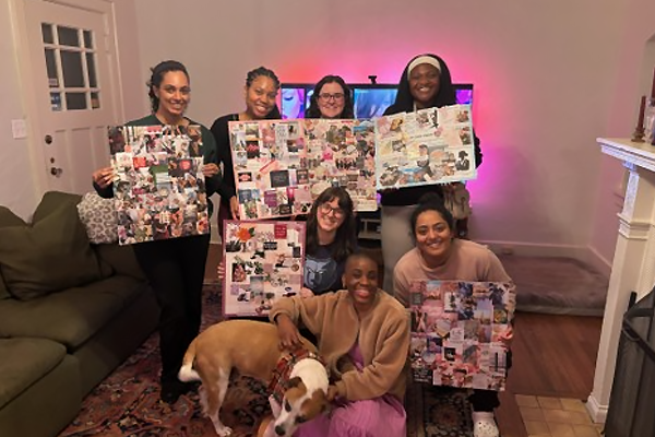 Residents displaying completed vision boards in a living room, with a dog in the foreground