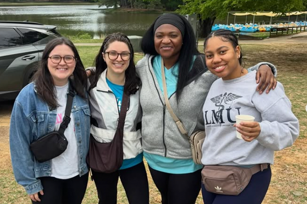 Four female residents at a retreat in front of a lake