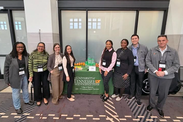 Residents and PD standing in a lobby in front of a table with UTHSC giveaways