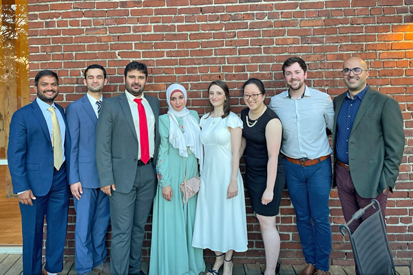 Group graduation picture taken outside against a brick wall