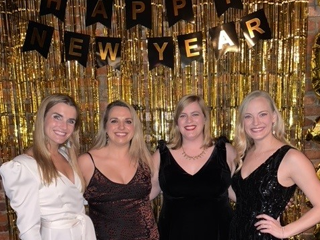 Four female residents standing before a Happy New Year banner